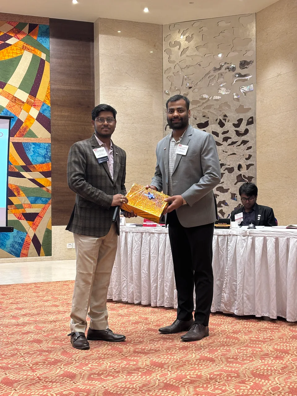 Roshan Burnwal and another BNI attendee holding a wrapped gift during a chapter gathering.