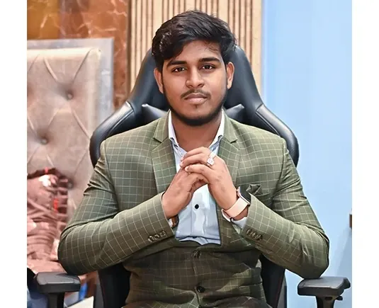 Roshan Burnwal seated in an office wearing a green checked suit.